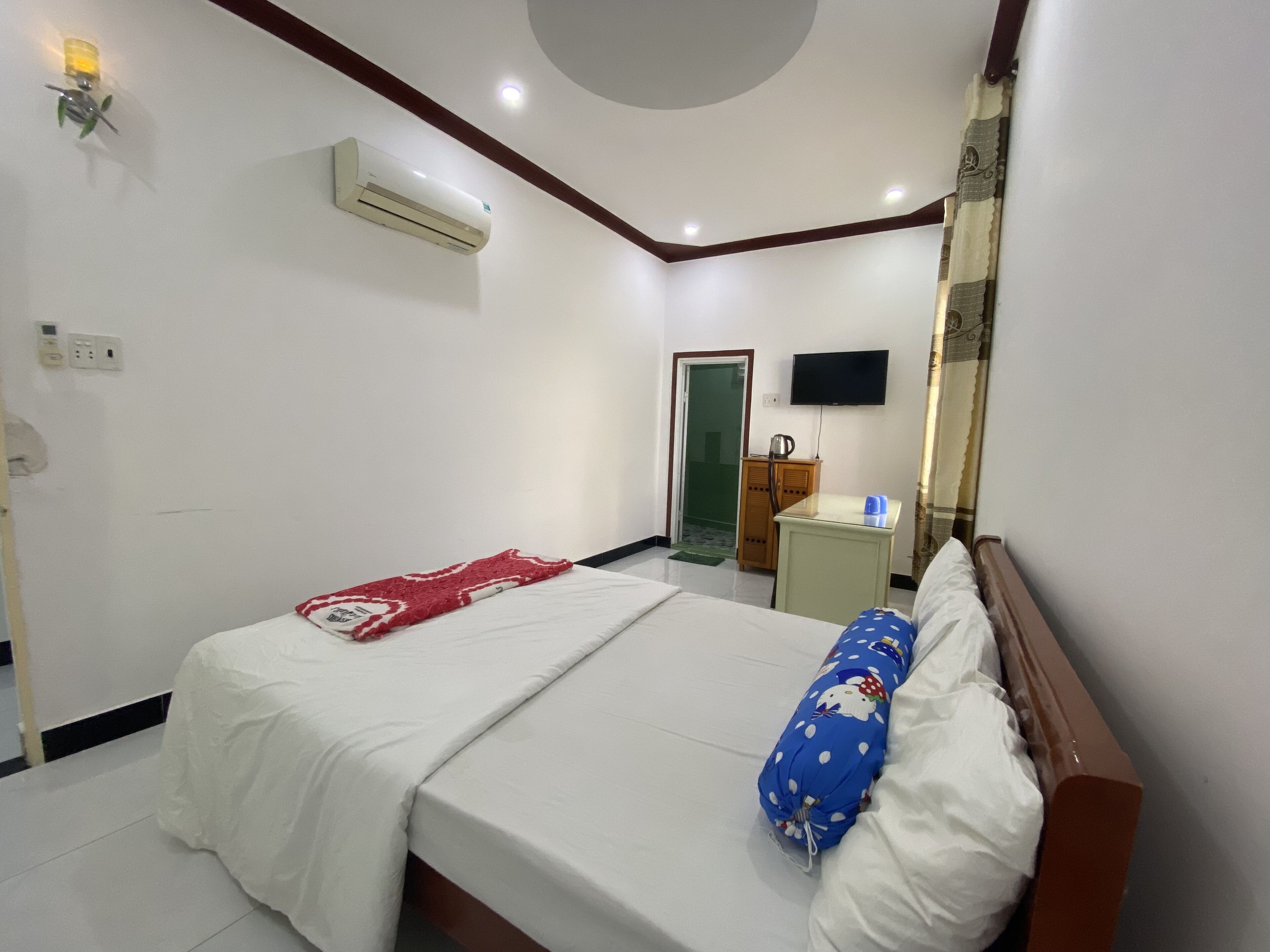 Une chambre d’hôtel équipée d’un lit, d’une télévision, d’un climatiseur et d’une petite armoire.