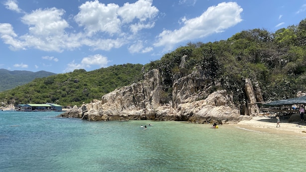 A coastal area with clear turquoise waters, rocky cliffs, and a beach. - Ninh Chu House (Ninh Chu)