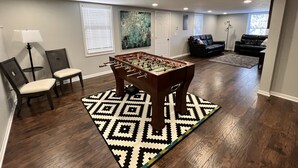 Una habitación con mesa de fútbol, sofá y lámpara.