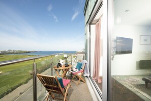 Ein Balkon mit Blick aufs Meer, ein Tisch mit einer Vase und zwei Stühle.