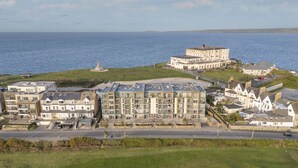 Un hotel sulla costa con diversi edifici, tra cui una torre imponente, situato vicino al mare.