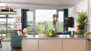 Una cucina moderna con un'isola grande, un'area pranzo con un divano e vista sulla campagna.