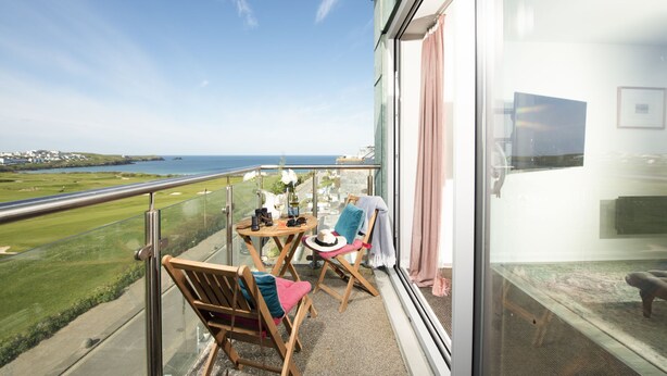 Un balcone con vista sul mare, un tavolo con un vaso e due sedie.