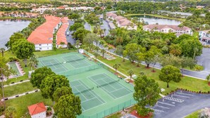 Pista de tenis rodeada de abundante vegetación y edificios residenciales.