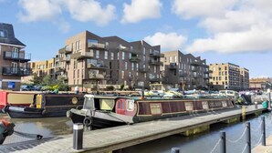 Un canal bordé de bateaux amarrés et, au fond, une rangée d’immeubles d’appartements modernes.