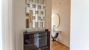 Une salle de bain moderne avec un meuble-lavabo en verre, un miroir fixé au mur et un élément décoratif en miroir.