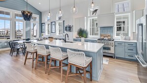 Una cocina amplia con una isla grande, armarios blancos y vistas al exterior.