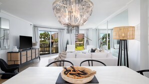 A modern living room with a large chandelier, white furniture, and a view of the outdoors. - Dancing Wave, Beachfront, Destin, Holiday Isle (Destin)