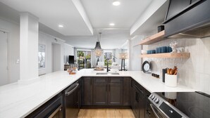 A modern kitchen with dark cabinets, white countertops, and a built-in stove. - Dancing Wave, Beachfront, Destin, Holiday Isle (Destin)