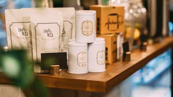 A display of tea products with white packaging and gold accents, arranged on a wooden shelf.