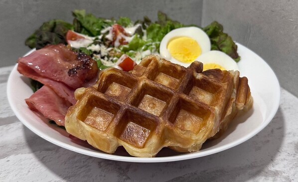 A plate with a waffle, boiled egg, ham, and salad. - Tokyo Guesthouse HIVE (Tokyo)