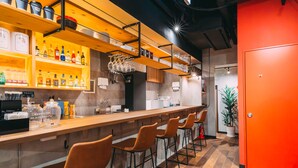 A bar area with wooden shelves, bar stools, and a counter with various bottles and glasses. - Tokyo Guesthouse HIVE (Tokyo)