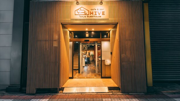 The entrance to a cafe and bar named HIVE in Tokyo, featuring a modern design with vertical wooden slats and a welcoming entrance. - Tokyo Guesthouse HIVE (Tokyo)