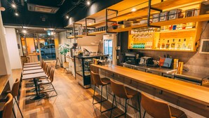 A modern bar area with wooden flooring, bar stools, and shelves stocked with bottles and glasses. - Tokyo Guesthouse HIVE (Tokyo)
