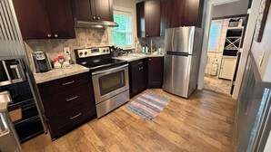 Una cocina moderna con armarios de madera oscura, electrodomésticos de acero inoxidable y piso de madera.