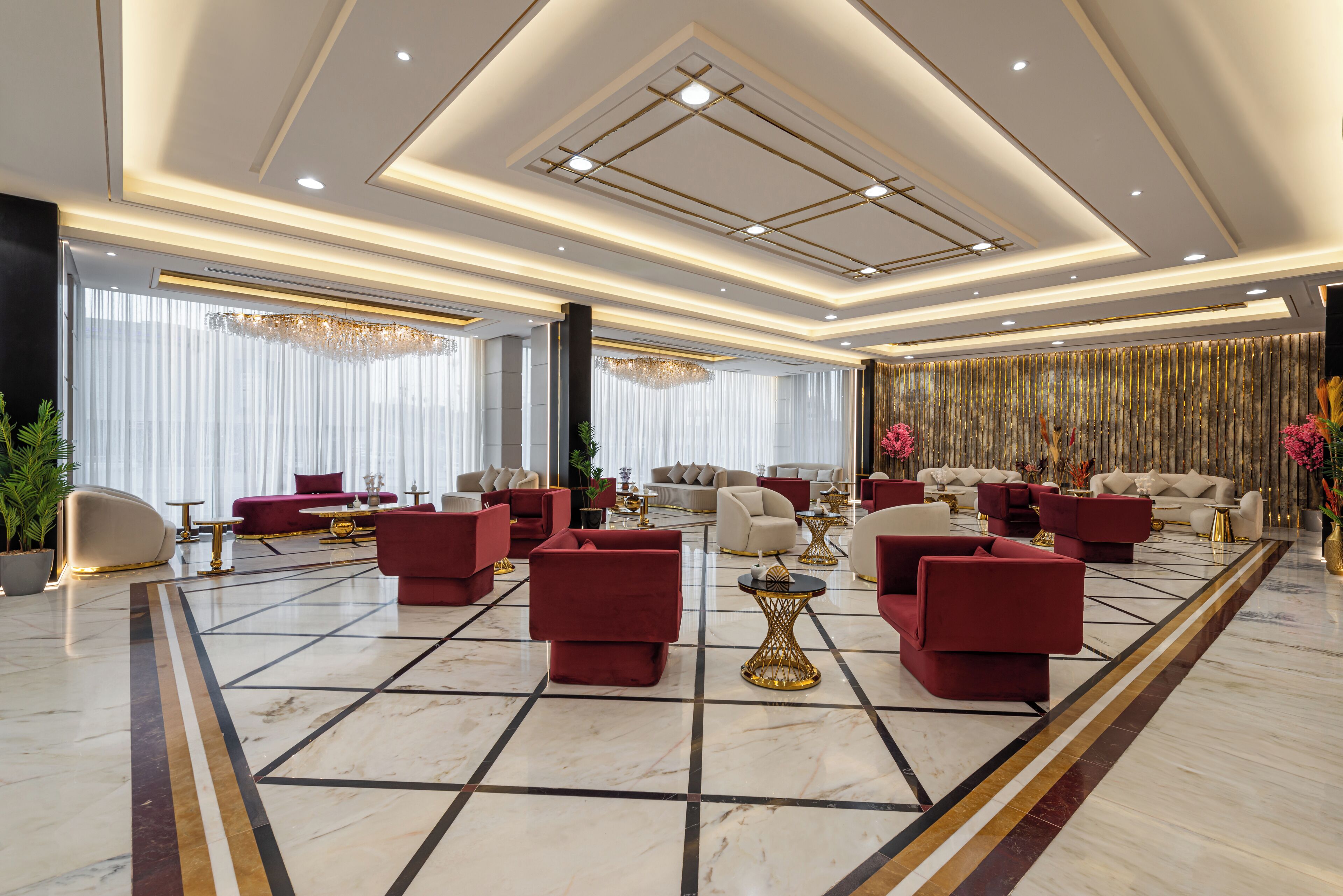 A spacious lobby with multiple seating areas, a marble floor, and a modern ceiling design.