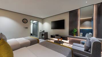 A modern hotel room with a large bed, two sofas, a small table, a TV, and a mirror.