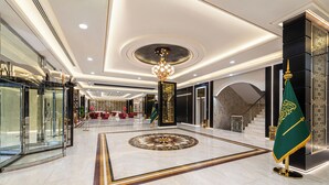A spacious lobby with a grand chandelier, marble flooring, and a staircase leading to upper floors. - Ross Hotel  (Riyadh)