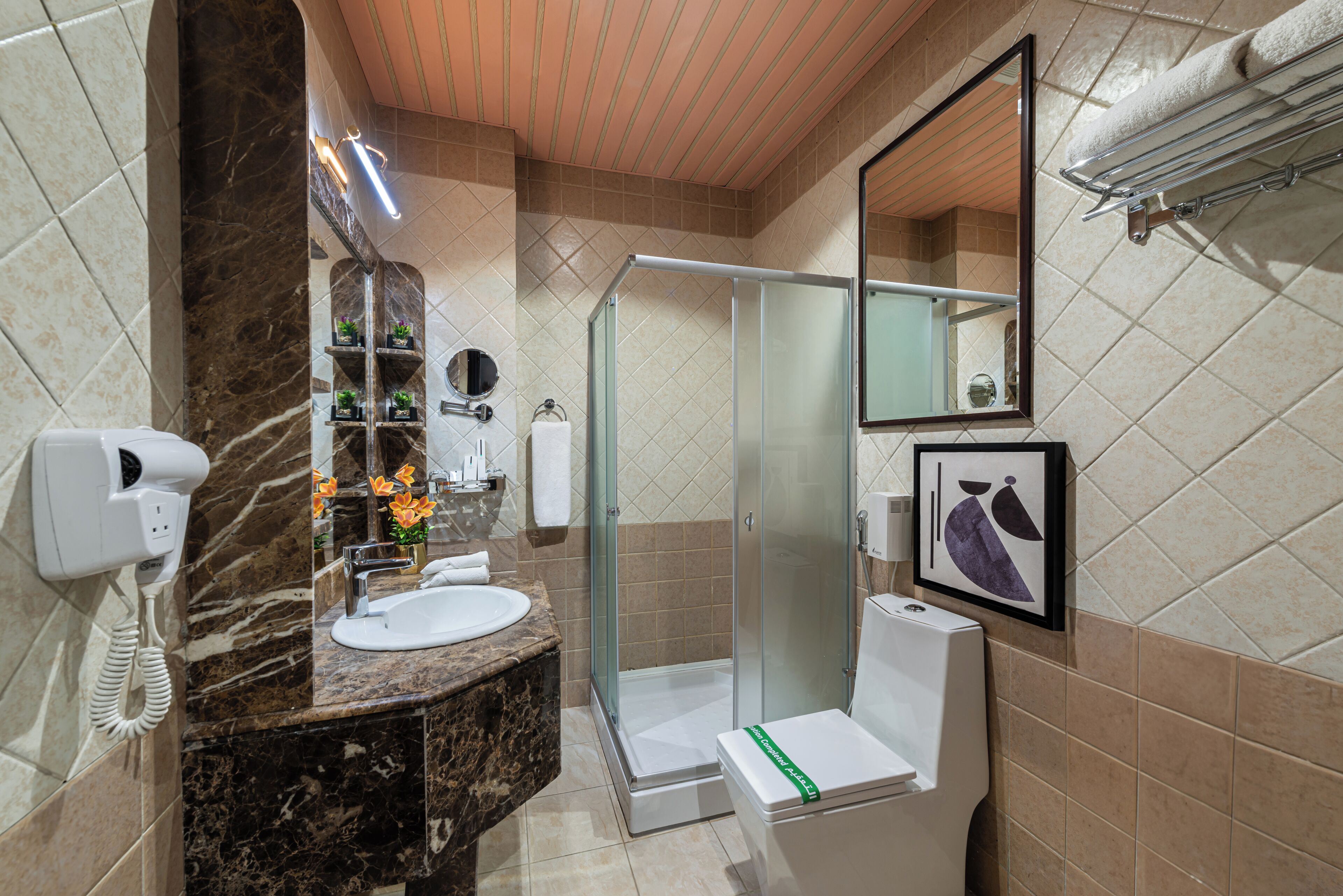 Une salle de bain moderne avec un lavabo en marbre, une douche en verre, des toilettes et un porte-serviettes.
