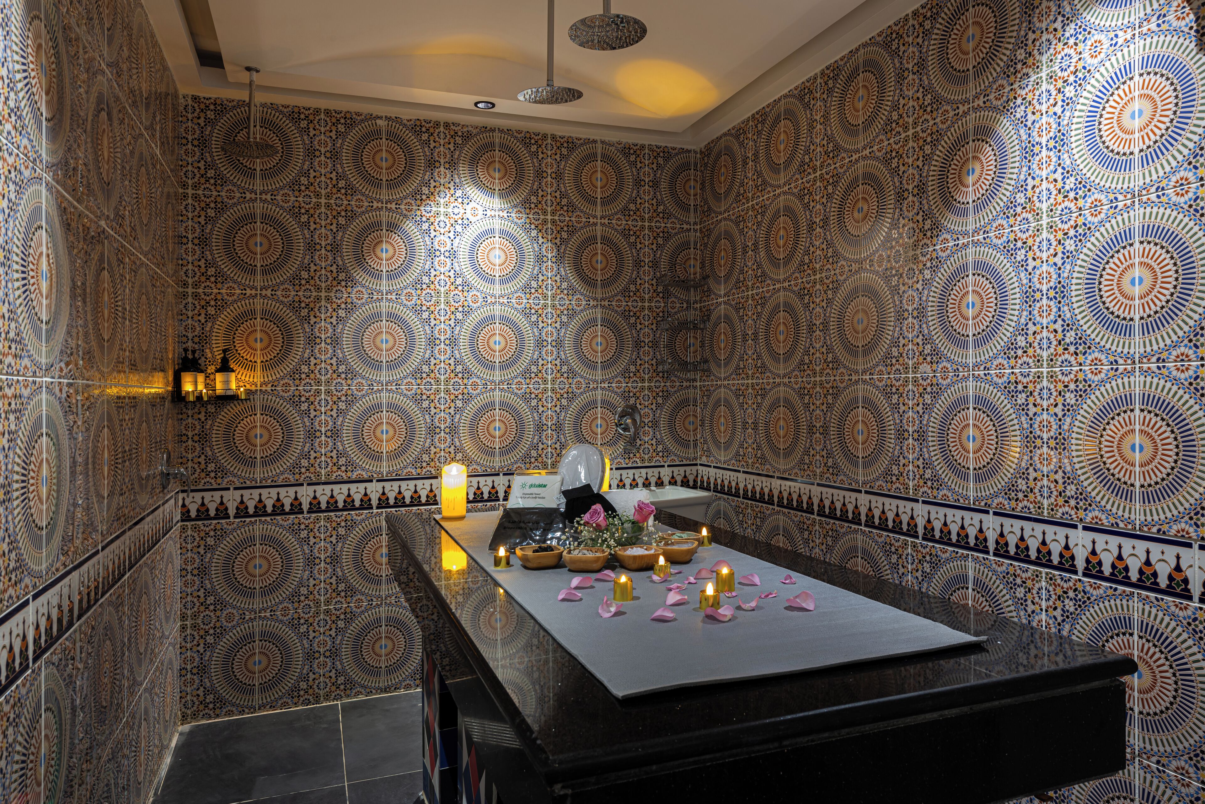 A room with patterned tile walls, a black reception desk, and candles.