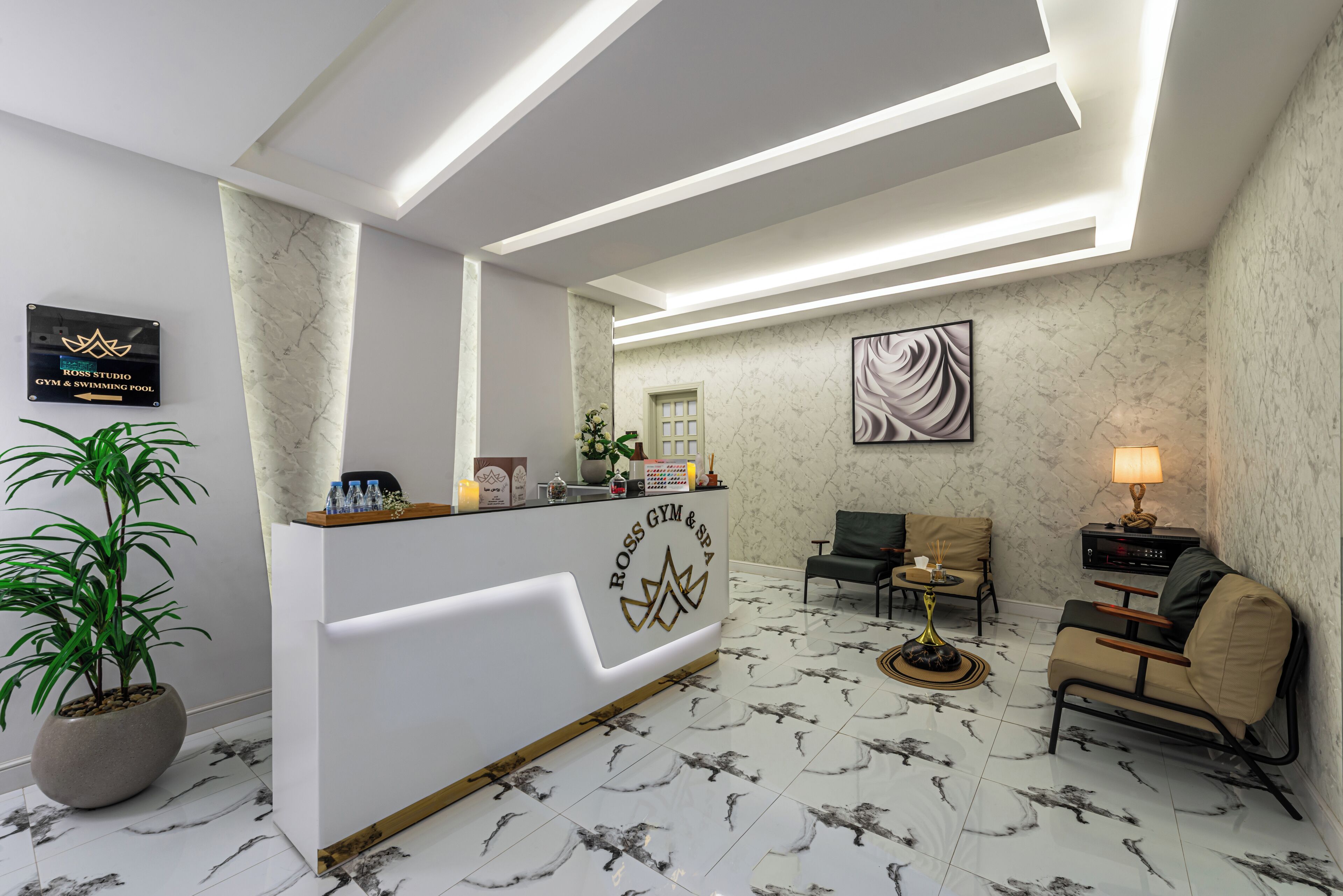 A reception area with a marble floor, a reception desk, a sofa, a chair, a lamp, and a potted plant.