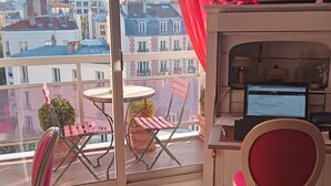 A balcony with a table, chairs, and a TV.