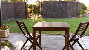 A patio with a wooden table and chairs, surrounded by a stone wall and a wooden fence. - Vineyard Suite for a couple in Historical Homestead, relax on family winery.  (Langhorne Creek)