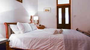 A neatly made bed with white linens, a wooden headboard, and a nightstand with a lamp and a framed picture. - Vineyard Suite for a couple in Historical Homestead, relax on family winery.  (Langhorne Creek)