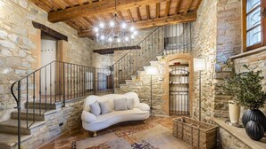 A stone-walled interior with a staircase, a white sofa, and a chandelier. - Charming villa in Chianni,Pool,garden, A/C, Pergola for al fresco dining,sleep 9 (Chianni)