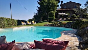 A swimming pool with a stone deck, surrounded by a landscaped garden and a stone house. - Charming villa in Chianni,Pool,garden, A/C, Pergola for al fresco dining,sleep 9 (Chianni)