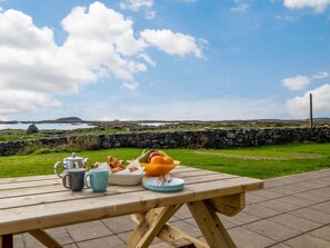 A picnic table with a view of a grassy area and a stone wall. - Lake House Mannin, Ballyconneely (Ballyconneely)