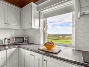 A kitchen with white cabinets, a microwave, and a bowl of fruit on the counter. - Lake House Mannin, Ballyconneely (Ballyconneely)