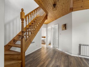 A wooden staircase leading to a bedroom with a white door and a radiator on the floor. - Lake House Mannin, Ballyconneely (Ballyconneely)