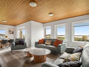 A spacious living area with a wooden ceiling, large windows, and a view of the landscape. - Lake House Mannin, Ballyconneely (Ballyconneely)
