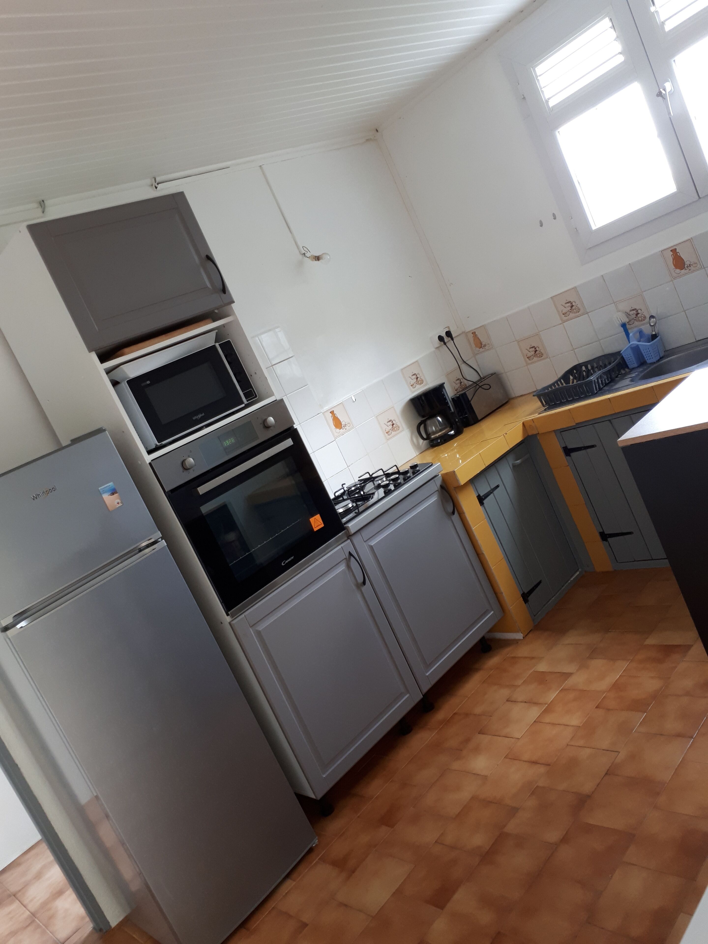 A compact kitchen with a refrigerator, oven, microwave, and gas stove.
