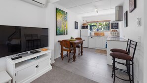 Un espace de vie compact comprenant un téléviseur à écran plat, une table à manger en bois et un coin cuisine.