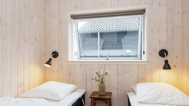 Une chambre avec deux lits, une fenêtre donnant sur un beau paysage et deux lampes fixées au mur.
