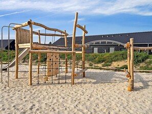 A wooden play structure on a sandy beach with a building in the background. - 5 Star Holiday Home in Romo (Rømø)