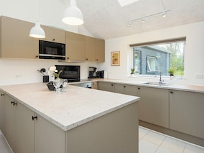 A modern kitchen with a central island, stainless steel appliances, and a window providing a view of the outdoors.