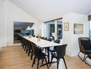 A modern dining area with a long table, black chairs, and pendant lighting. - 5 Star Holiday Home in Romo (Rømø)
