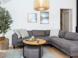 A modern living room with a grey sectional sofa, a round wooden coffee table, and a potted plant.