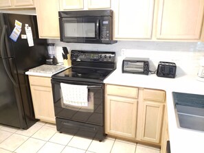 A kitchen with a black refrigerator, a microwave, a stove, a toaster, and wooden cabinets. - Located in walking distance to the heart of surf city.
515 N. Shore Surf City (Surf City)