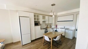 A modern kitchen with white cabinetry, a dining table with chairs, and a wooden floor.