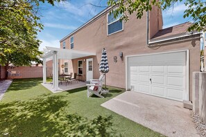 A house with a garage, a covered patio with chairs, and a tree. - Peaceful 3bd/2.5ba home w/ yard, garage (Albuquerque)