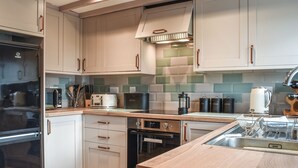 A modern kitchen with white cabinets, stainless steel appliances, and a wooden countertop.