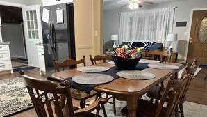 A dining area with a wooden table, chairs, and a basket of snacks.