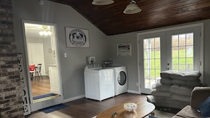 A spacious living room with a large couch, a wooden coffee table, and a laundry area with a washing machine and dryer.