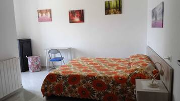 Una camera da letto con un letto, una sedia, una scrivania e tre quadri appesi al muro.