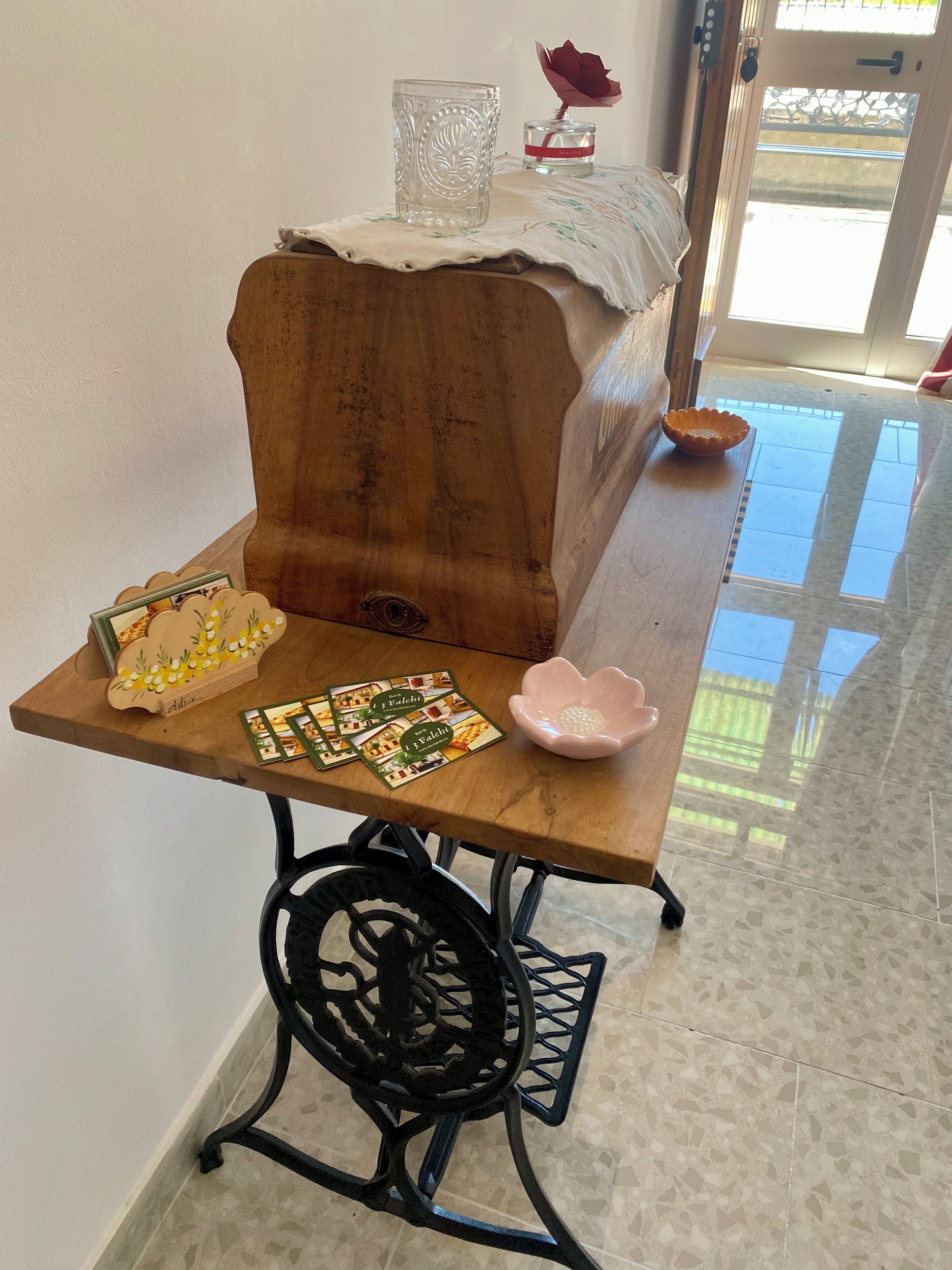 Een houten tafel met een glas en een roos, een houten kast en een kleine schaal.