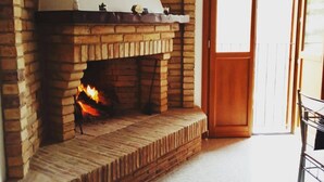 A brick fireplace with a white mantel and decorative items, a wooden door, and a tiled floor. - I 3 falchi Bed & Breakfast (Pennadomo)